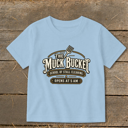 Light blue t-shirt with "The Muck Bucket School of Stall Cleaning Opens at 5 AM" graphic.
