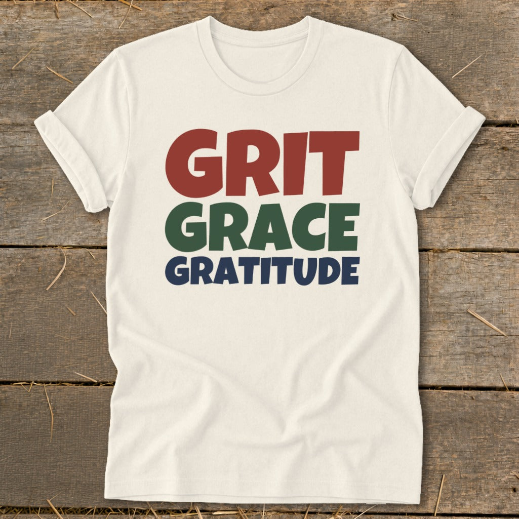 Off-white short-sleeve t-shirt with the words Grit, Grace, and Gratitude printed on the chest in red, green, and blue.