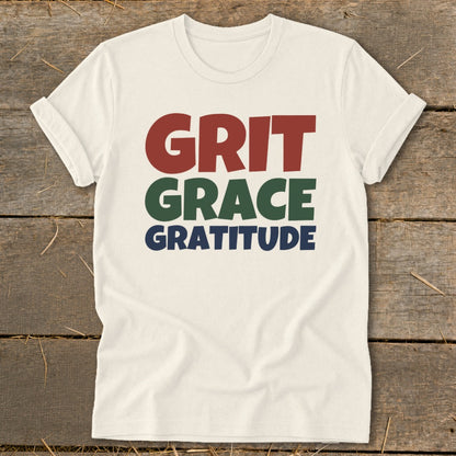 Off-white short-sleeve t-shirt with the words Grit, Grace, and Gratitude printed on the chest in red, green, and blue.