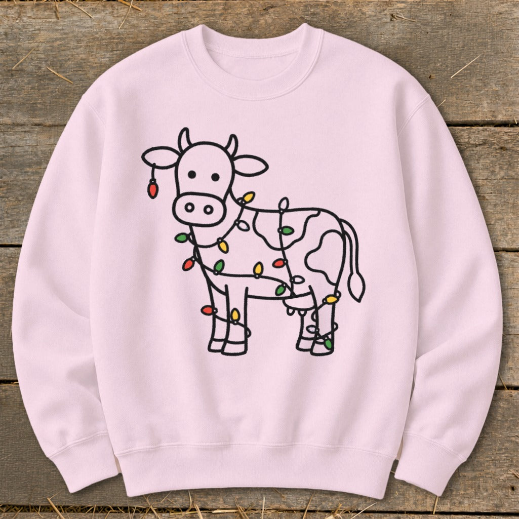 Pink sweatshirt with a cartoon cow wrapped in colorful Christmas lights.
