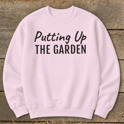 Pink crewneck sweatshirt with black text "Putting Up THE GARDEN"