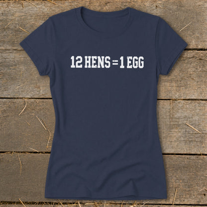 Navy blue women's t-shirt featuring the white distressed text 12 HENS = 1 EGG, laid flat on rustic wood.