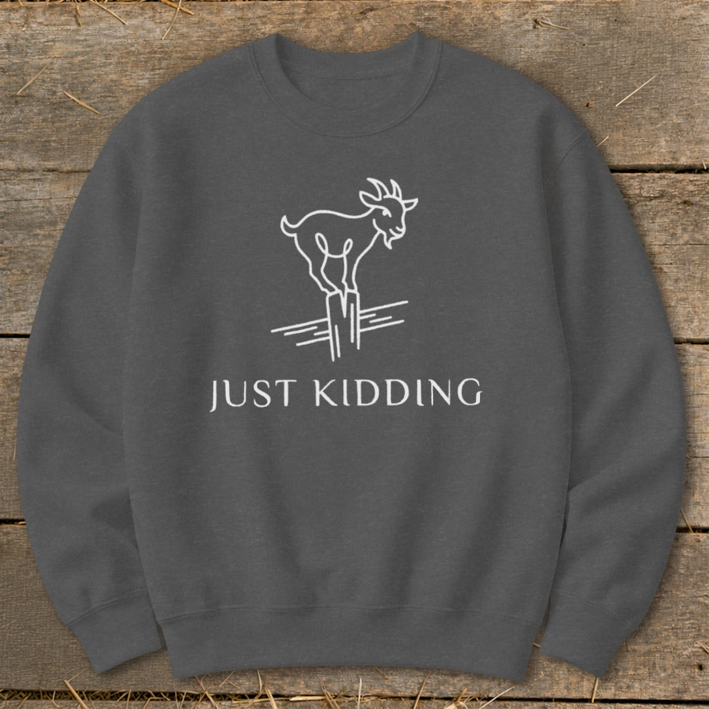 Dark gray sweatshirt with white line art of a goat and text reading "JUST KIDDING."
