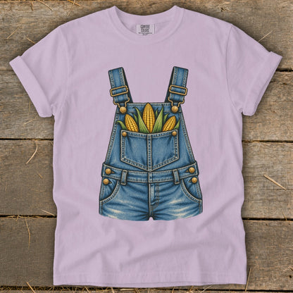 Light purple t-shirt with a graphic of denim overalls filled with corn.