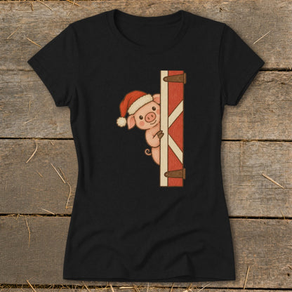 Black t-shirt with a peeking pig wearing a Santa hat by a barn door.