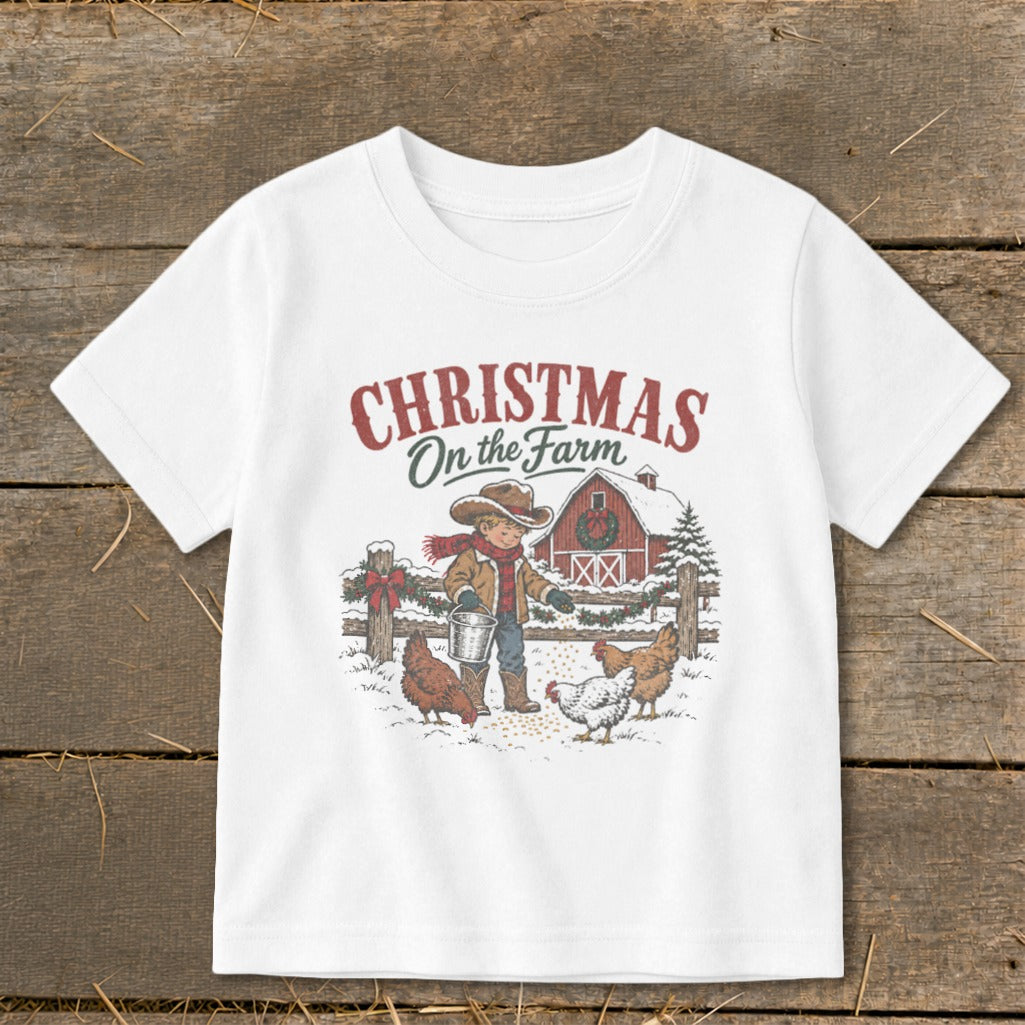 White t-shirt with Christmas on the Farm graphic of boy feeding chickens by a barn.