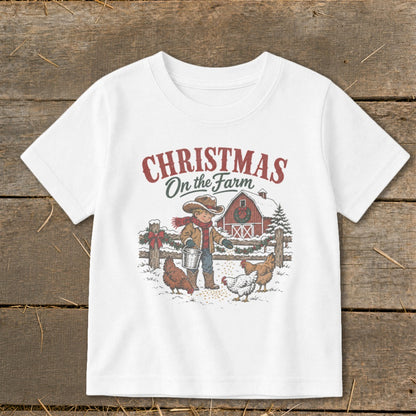 White t-shirt with Christmas on the Farm graphic of boy feeding chickens by a barn.