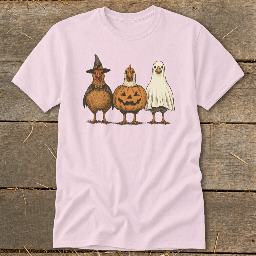 Three chickens dressed as a witch, pumpkin, and ghost on a pink t-shirt.