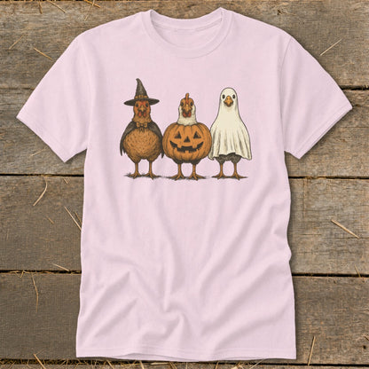 Three chickens dressed as a witch, pumpkin, and ghost on a pink t-shirt.