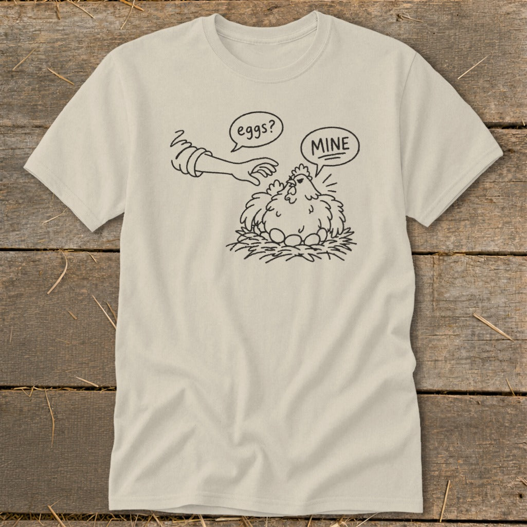 Light tan t-shirt with black line drawing of a chicken protecting eggs, saying "MINE".