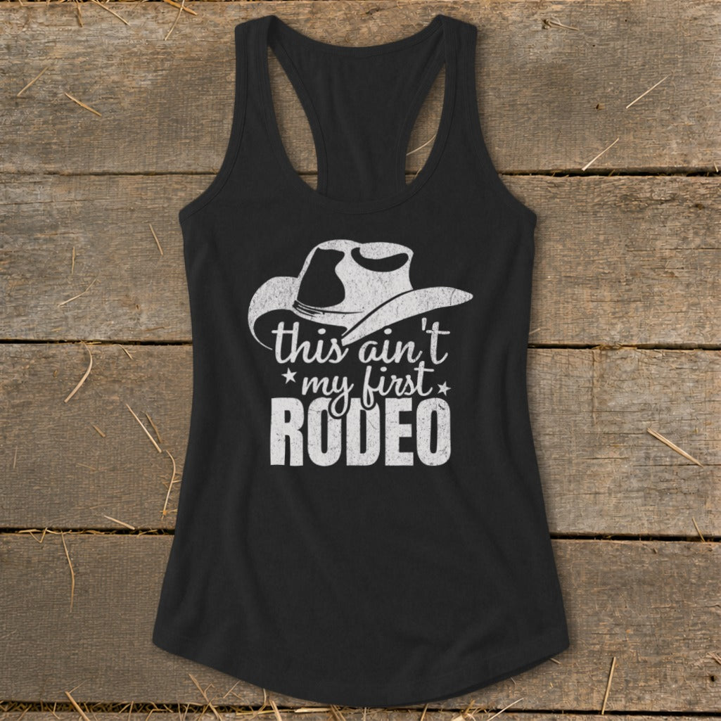 Black racerback tank top with white cowboy hat graphic and text: "this ain't my first RODEO".