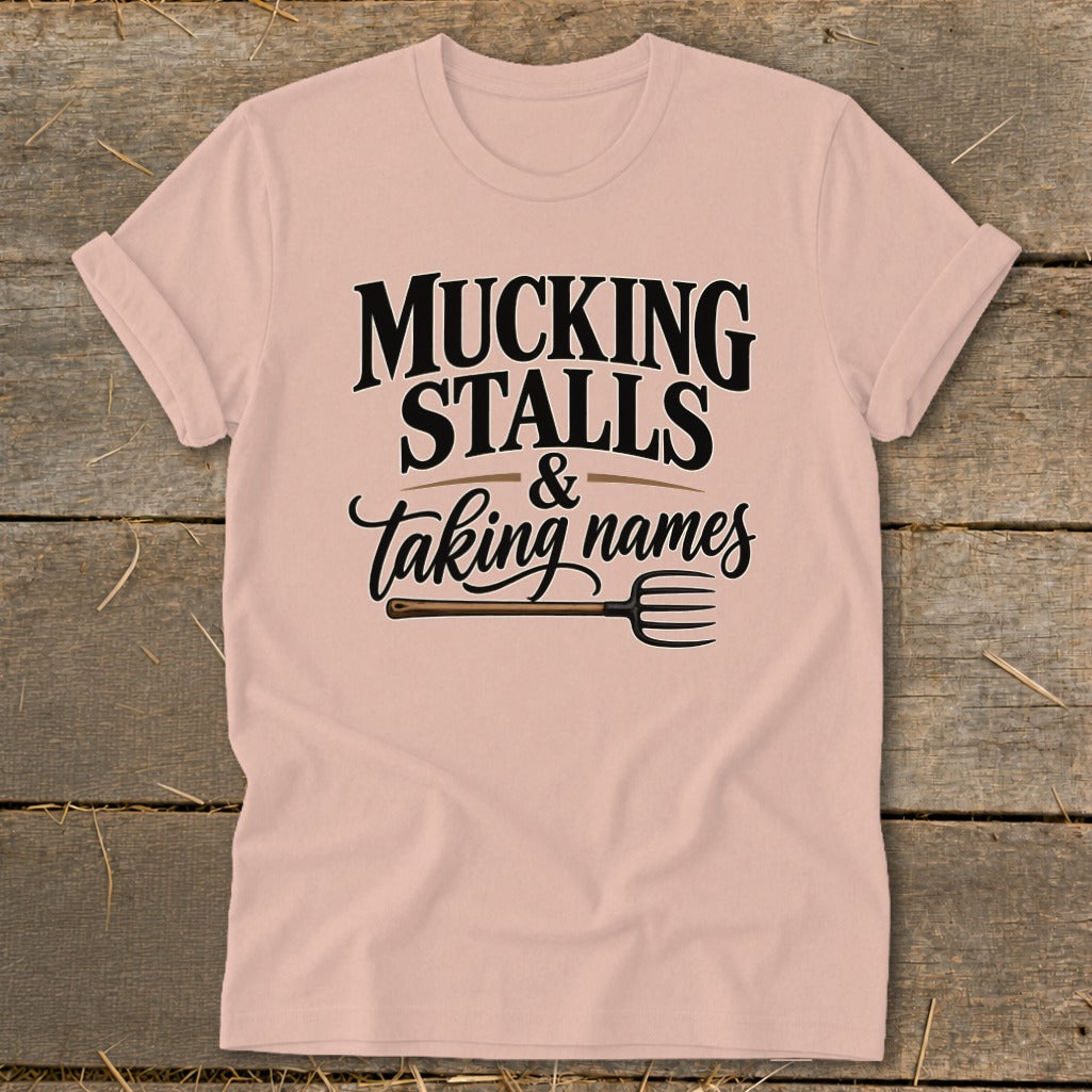 Pink t-shirt with "Mucking Stalls & Taking Names" and a pitchfork graphic.