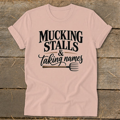 Pink t-shirt with "Mucking Stalls & Taking Names" and a pitchfork graphic.