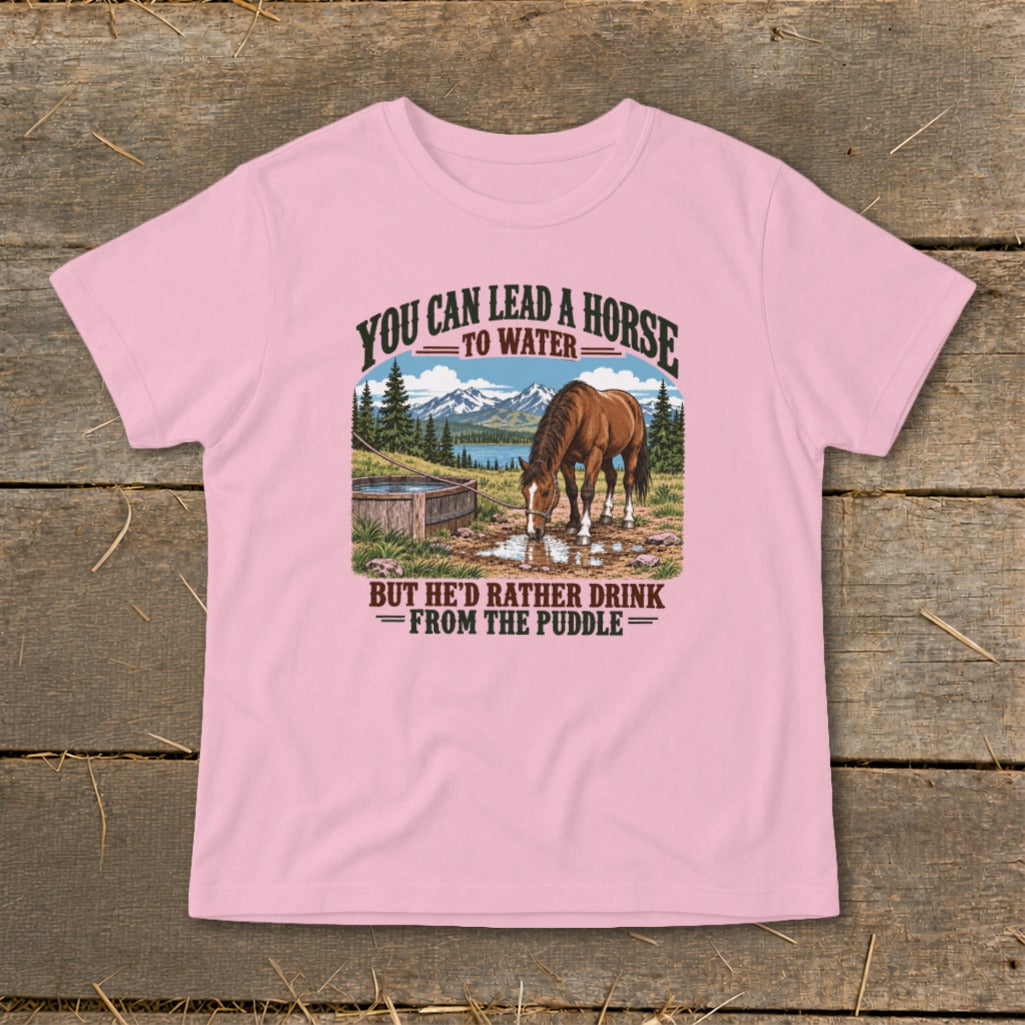 A pink t-shirt featuring a graphic of a horse drinking from a puddle with mountains behind it.