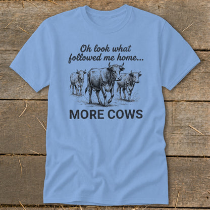 Light blue t-shirt with sketch of three cows and text "Oh look what followed me home... MORE COWS".