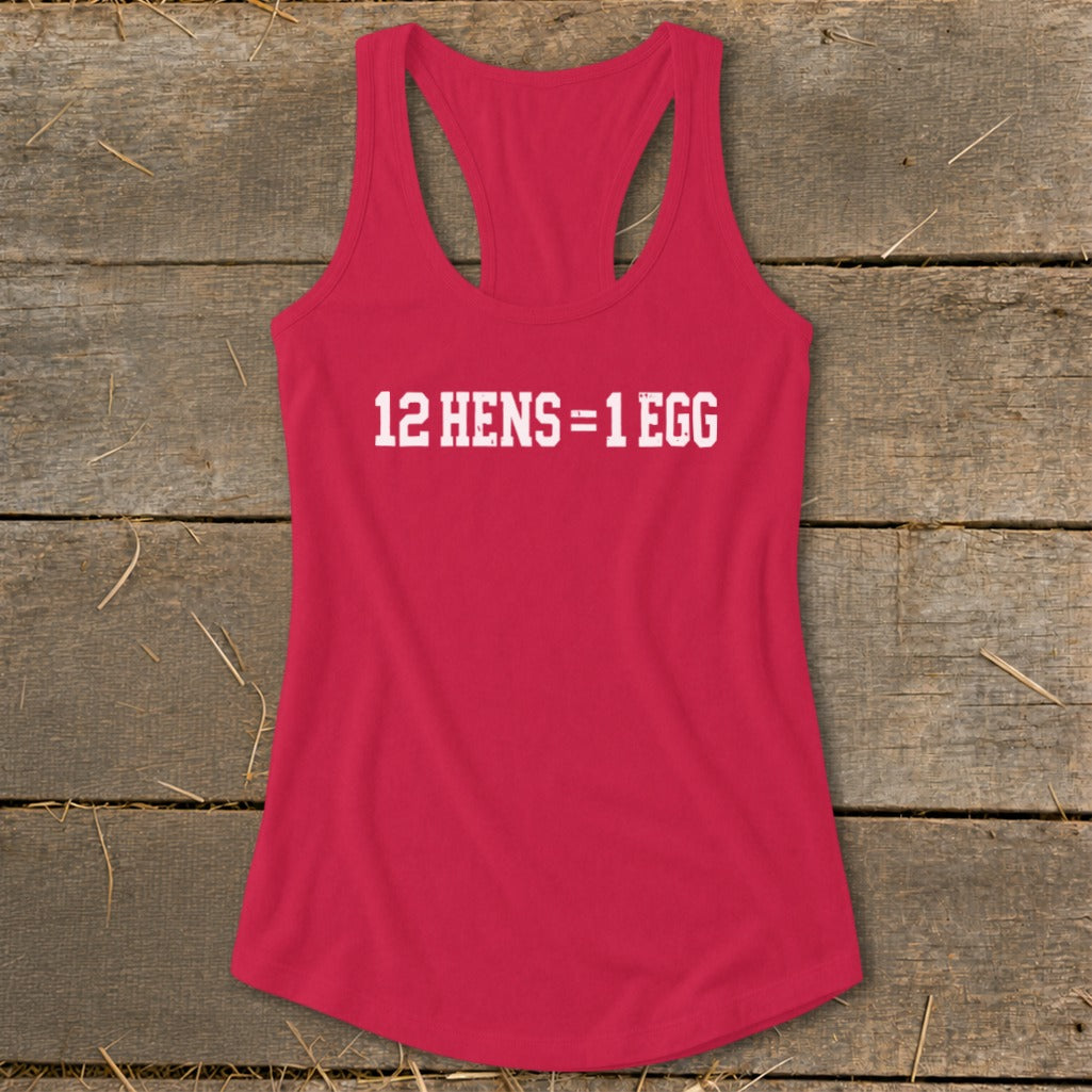 A red women's racerback tank top featuring the white text 12 HENS = 1 EGG laid flat on a rustic wooden background.