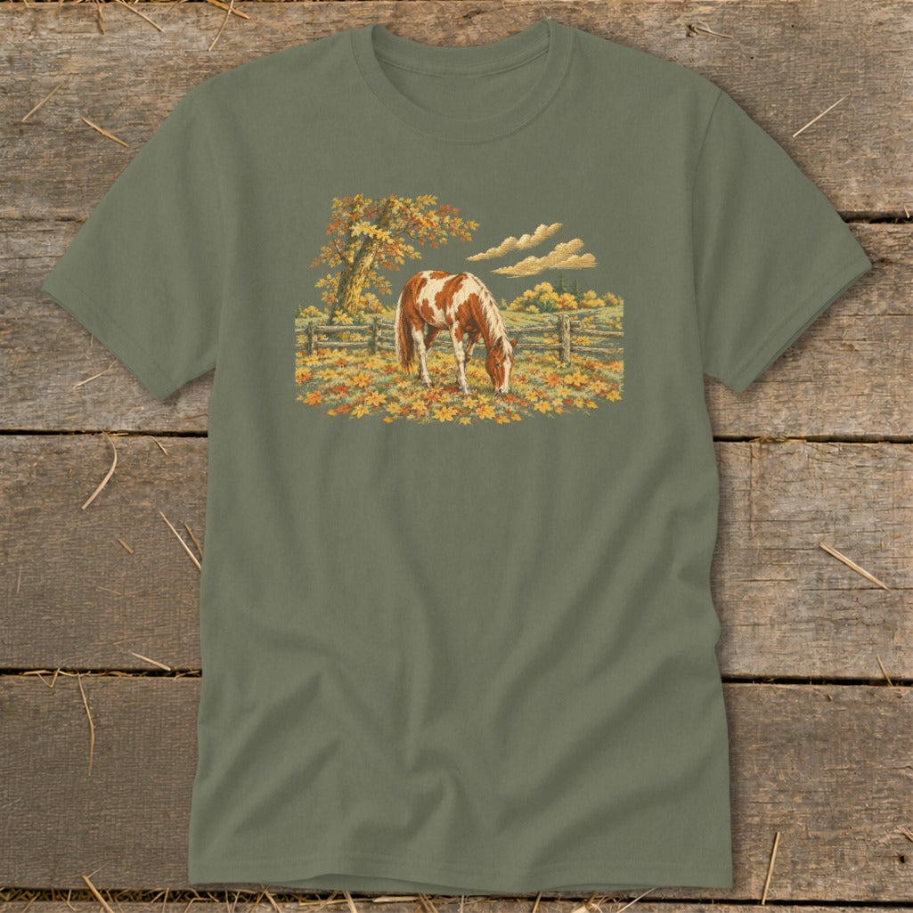 Horse grazing in a field of fallen autumn leaves with a wooden fence.