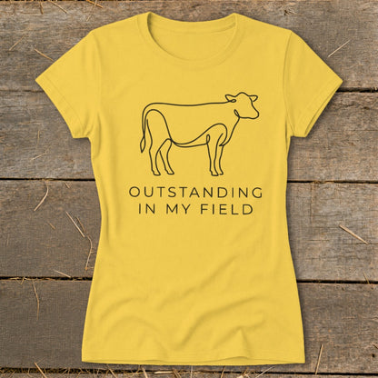Yellow t-shirt with line art cow and text "OUTSTANDING IN MY FIELD".