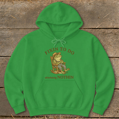 Green hoodie with a frog in a rocking chair and text "fixin to do absolutely nothin."