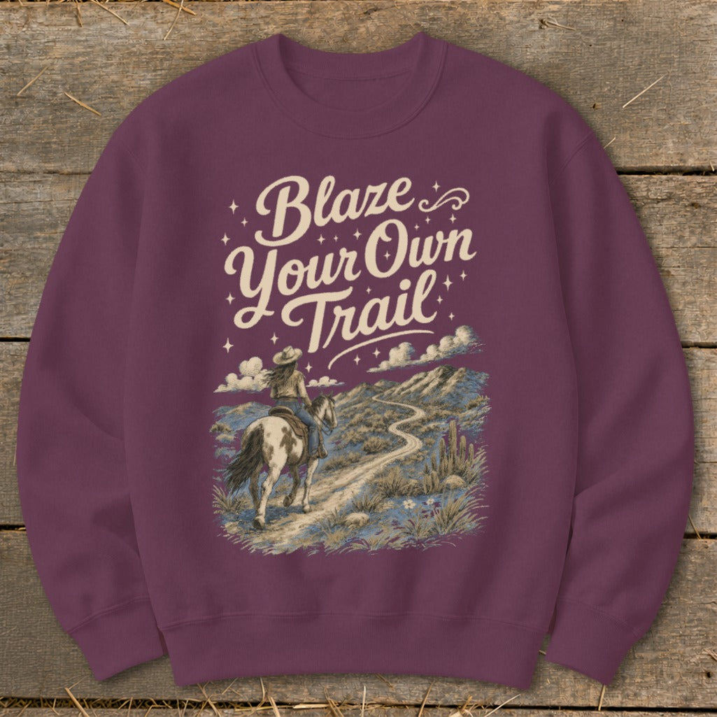 Maroon sweatshirt with "Blaze Your Own Trail" text and a woman riding a horse through a desert landscape.