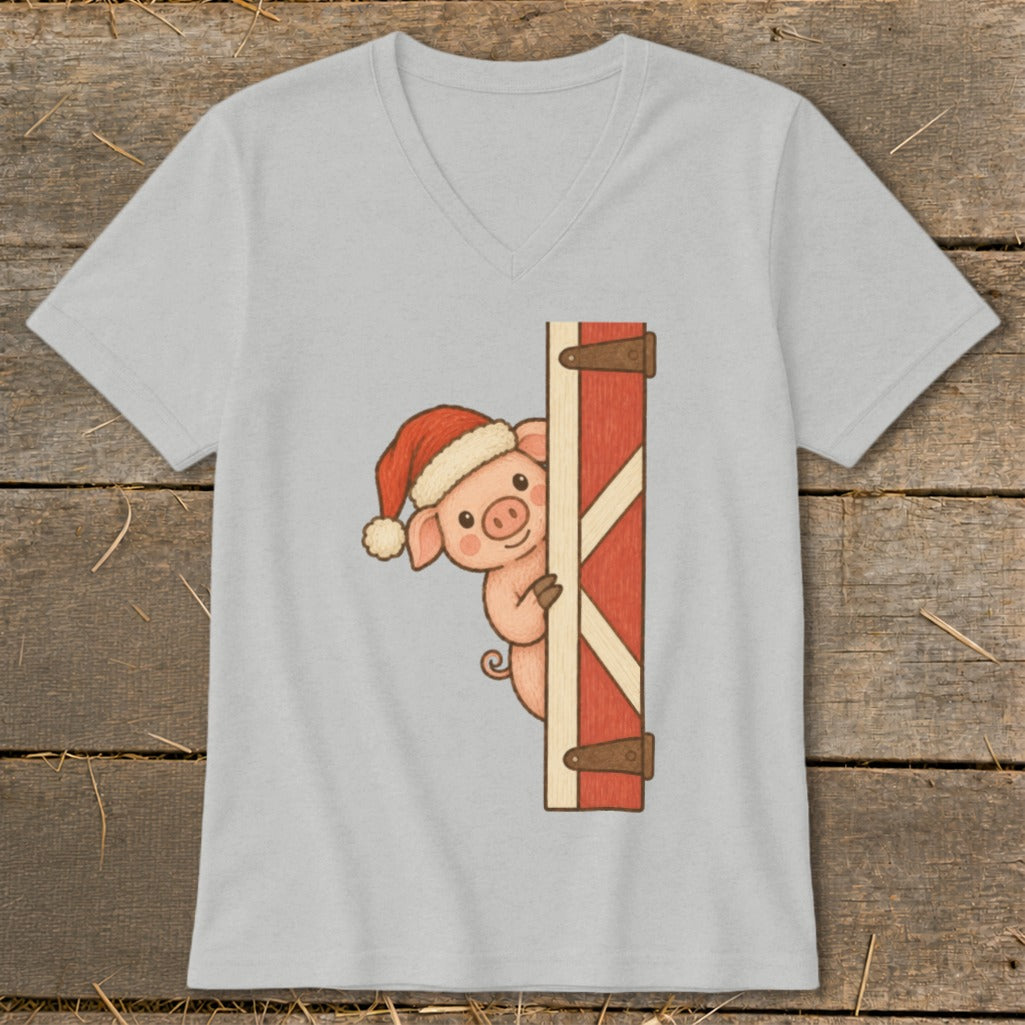 Pig wearing a Santa hat peeks from behind a red barn door.