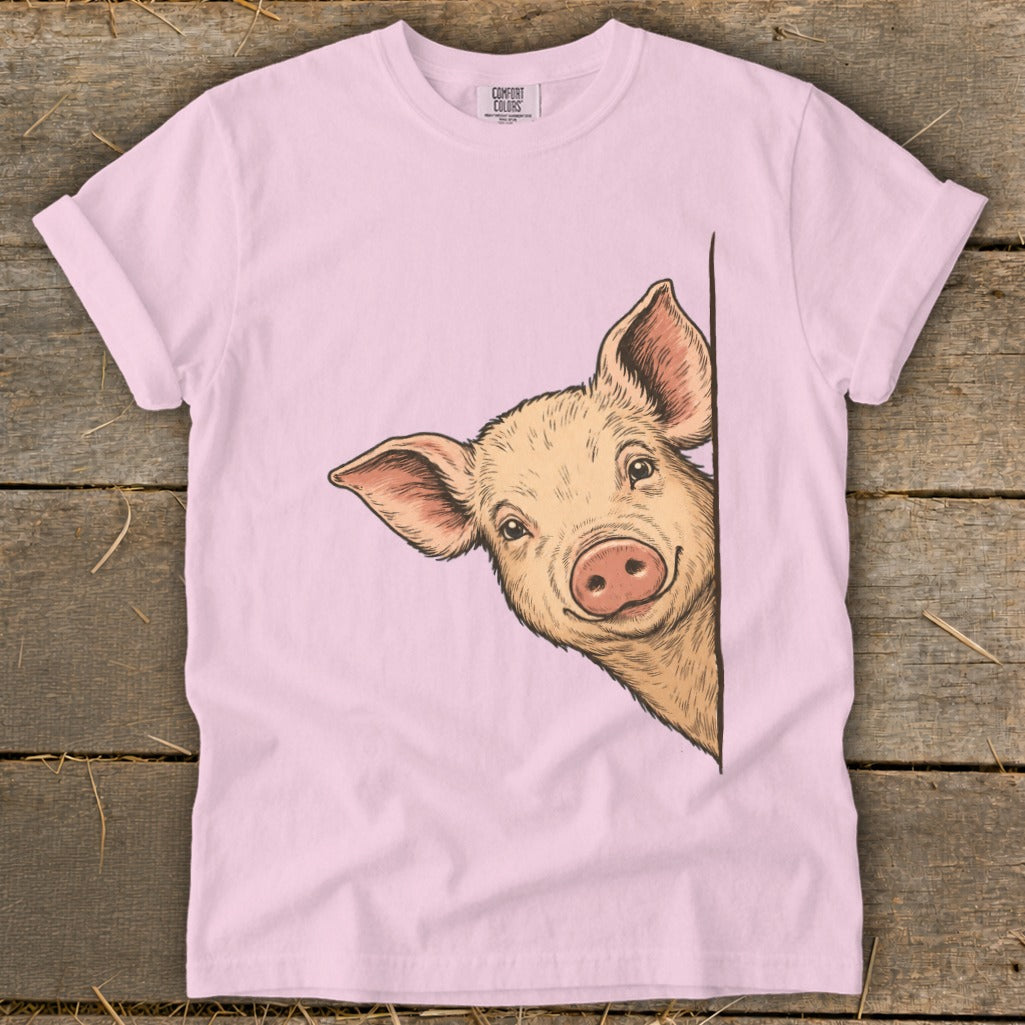 Pink t-shirt with a drawing of a pig peeking around a corner.