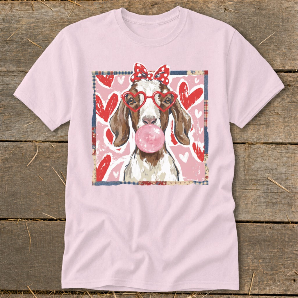 Light pink t-shirt with a graphic of a goat wearing a bow and heart glasses blowing bubblegum.