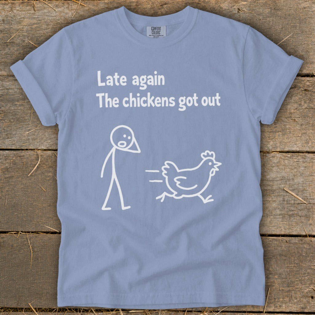 Light blue t-shirt with a stick figure and a running chicken, text says "Late again The chickens got out".