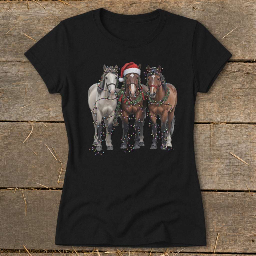 Three horses, one with a Santa hat, decorated with Christmas lights and garland.