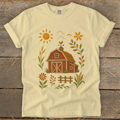 Light yellow t-shirt with a barn, sun, flowers, and corn graphic.