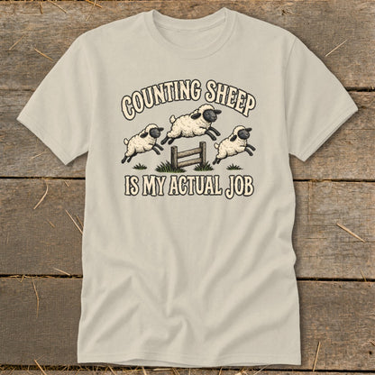 T-shirt with three sheep jumping over a fence and the text "Counting Sheep Is My Actual Job."