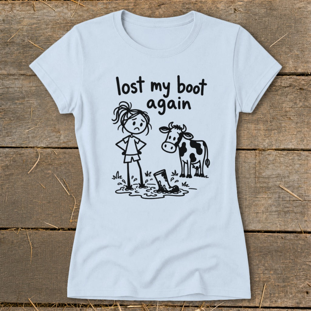 Light blue t-shirt featuring a cartoon of a girl and a cow looking at a muddy boot, with the text lost my boot again.