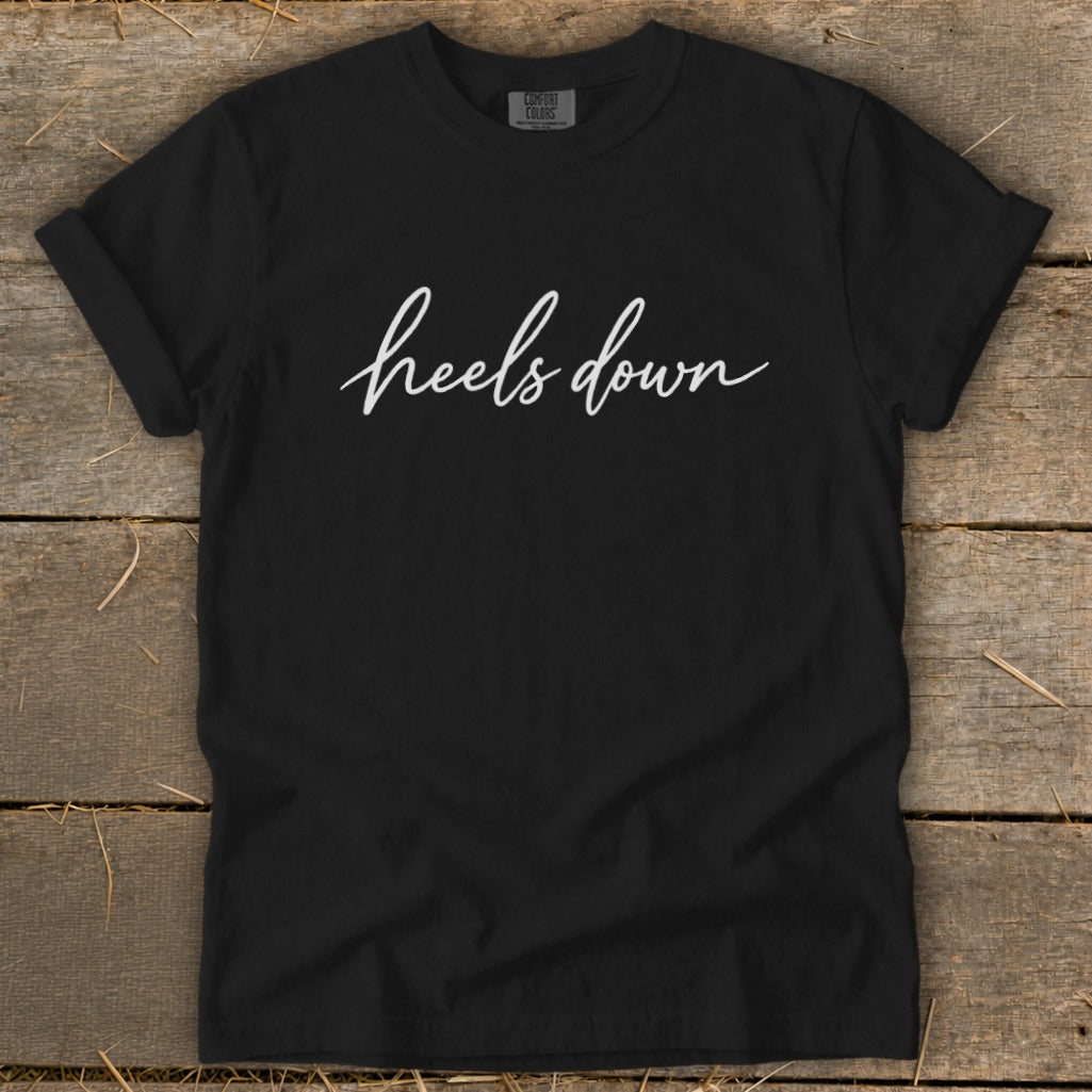 Black Comfort Colors t-shirt with white "heels down" script graphic.
