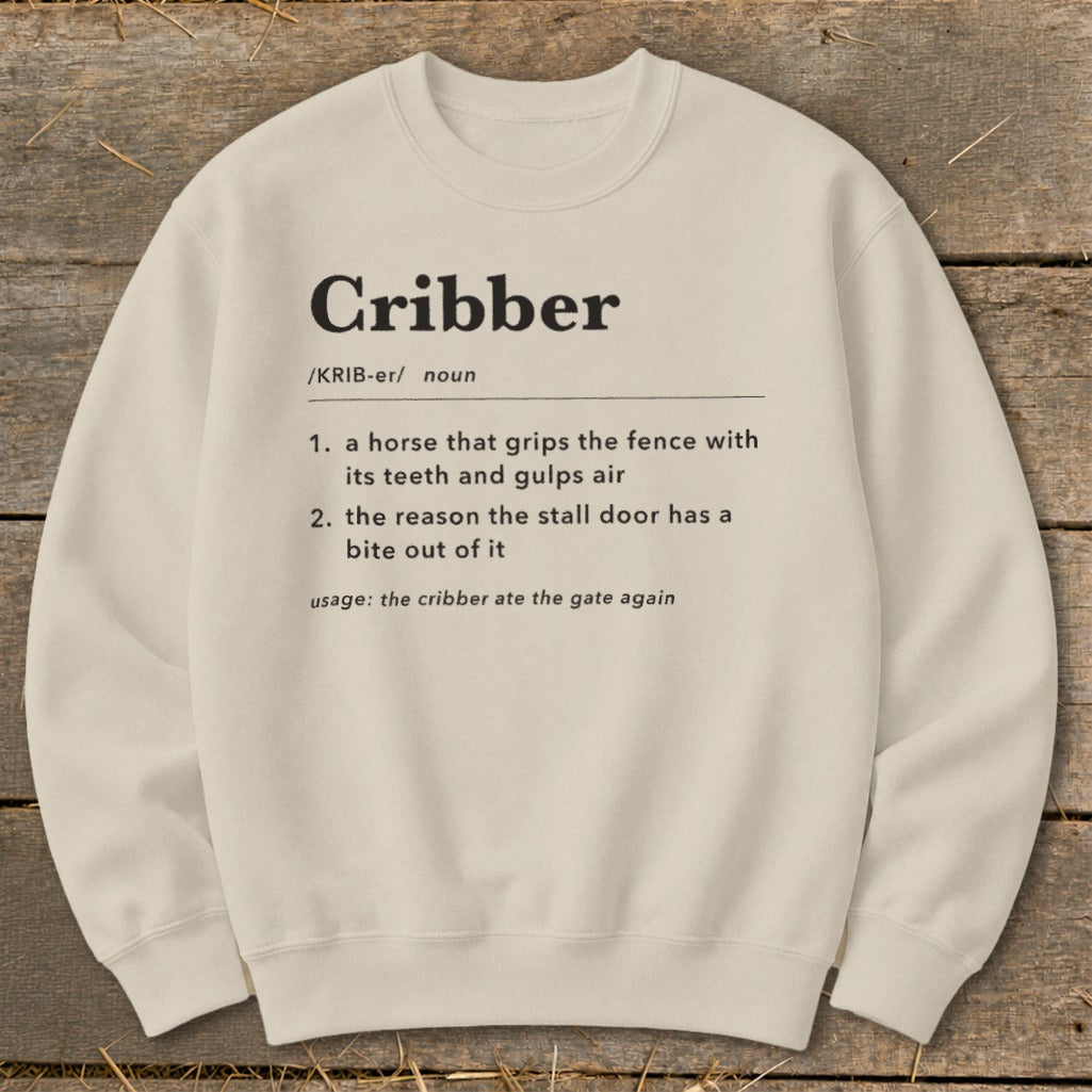 Beige crewneck sweatshirt featuring a dictionary-style definition of the word cribber printed in black text.