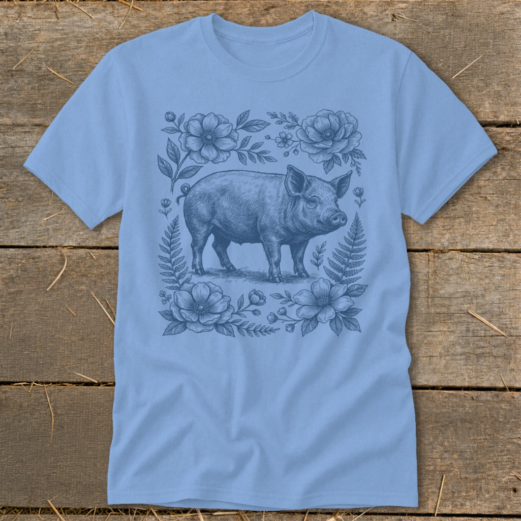 Light blue t-shirt with a vintage sketch of a pig surrounded by flowers and ferns.