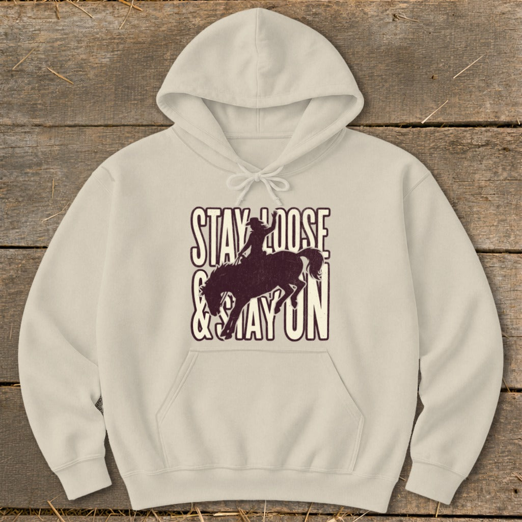 Cream hoodie with "STAY LOOSE & STAY ON" text and cowboy on horseback graphic.