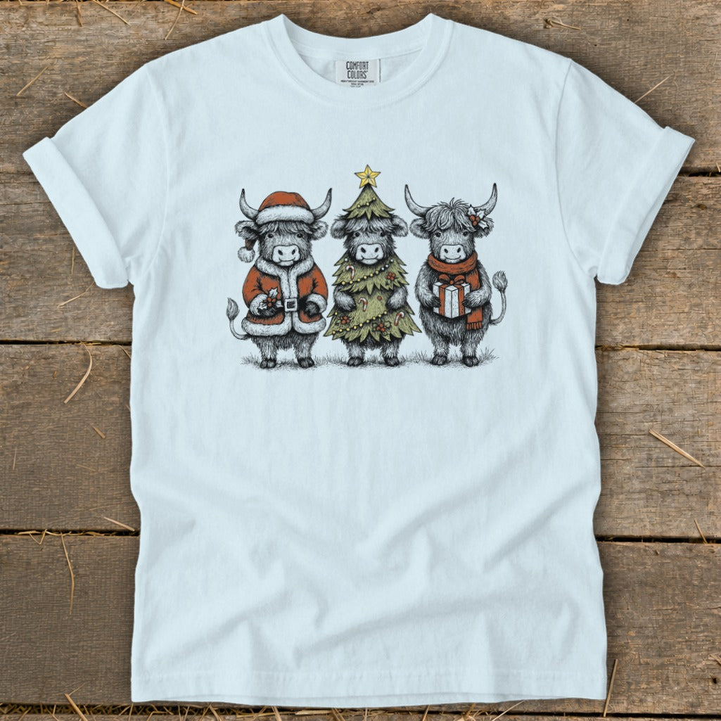 Three highland cows in festive Christmas attire on a white t-shirt.