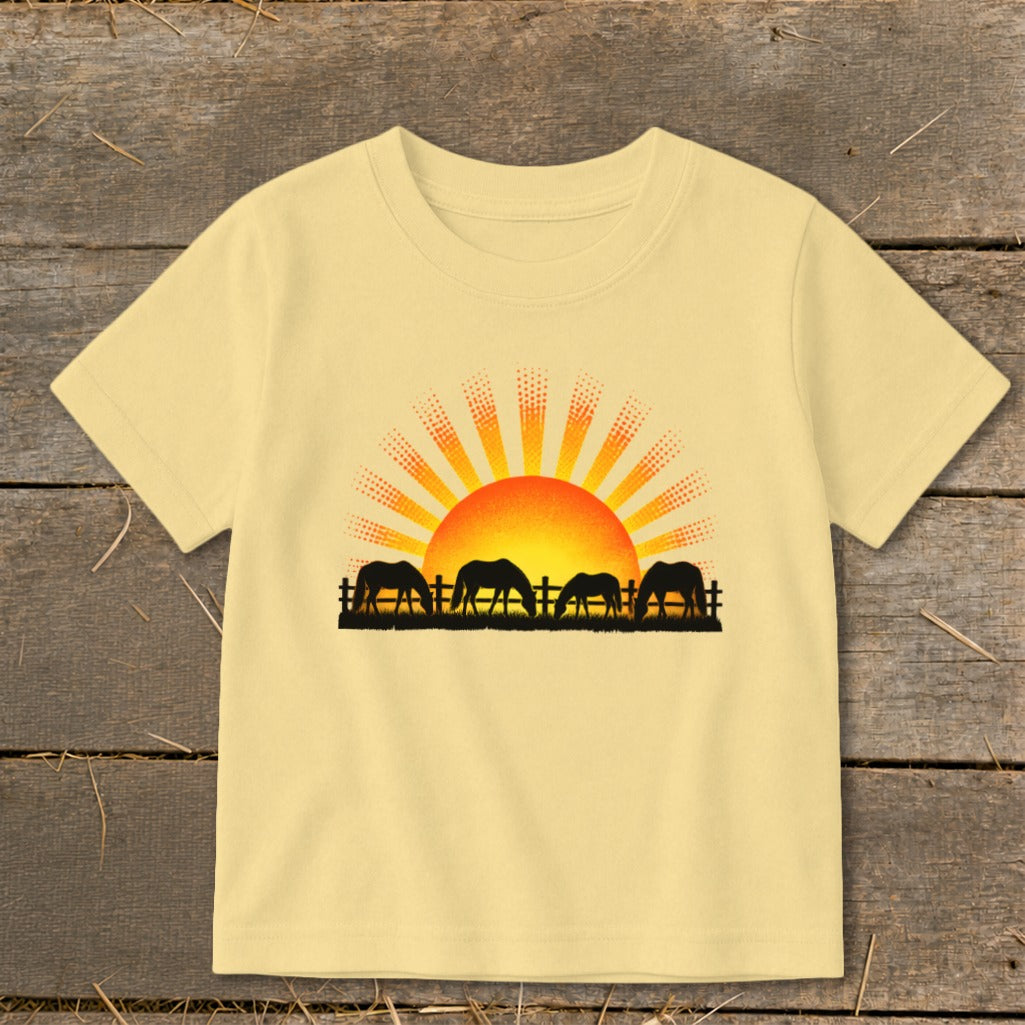 Yellow t-shirt with black silhouette of horses grazing at sunrise.