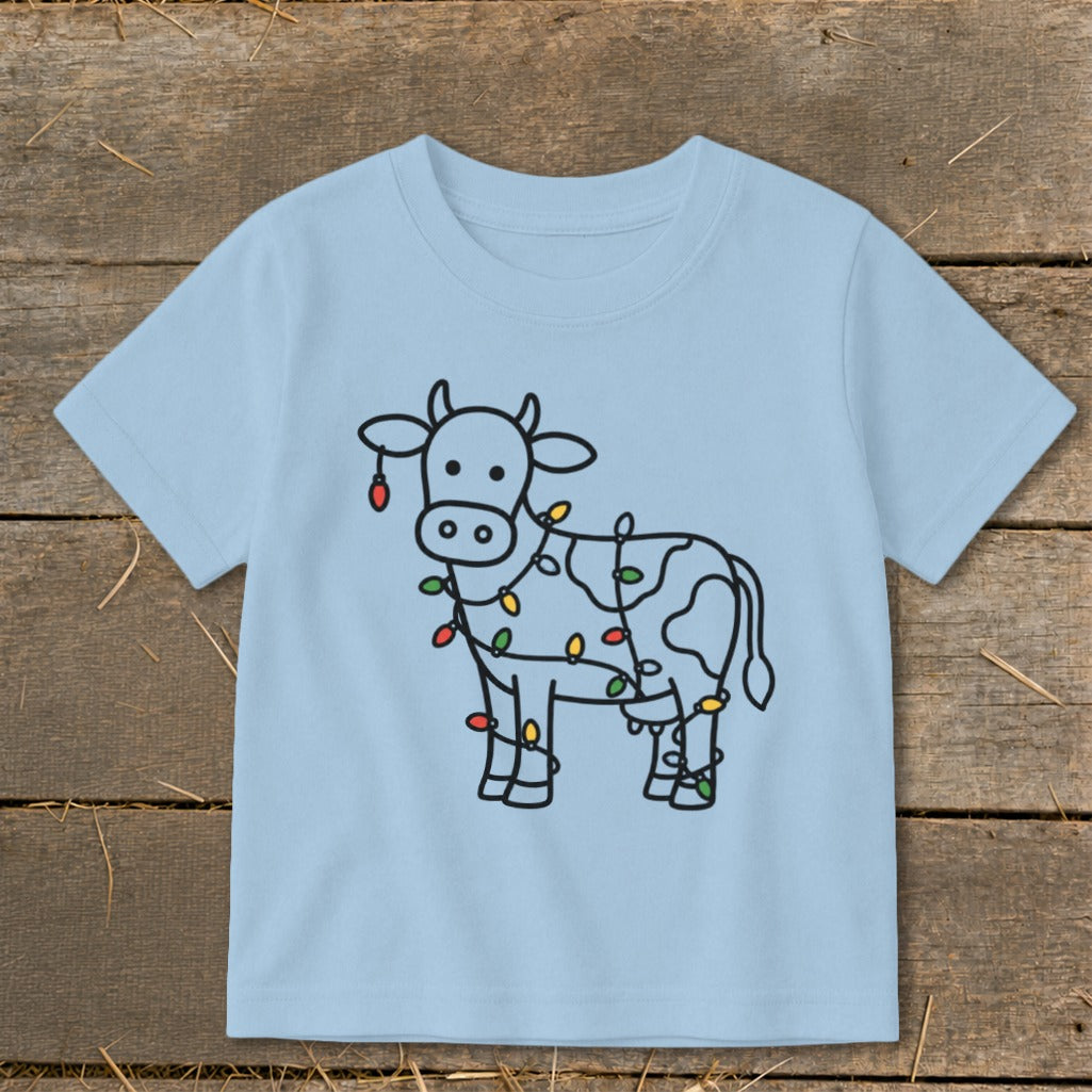 Light blue t-shirt with a black line drawing of a cow decorated with colorful Christmas lights.