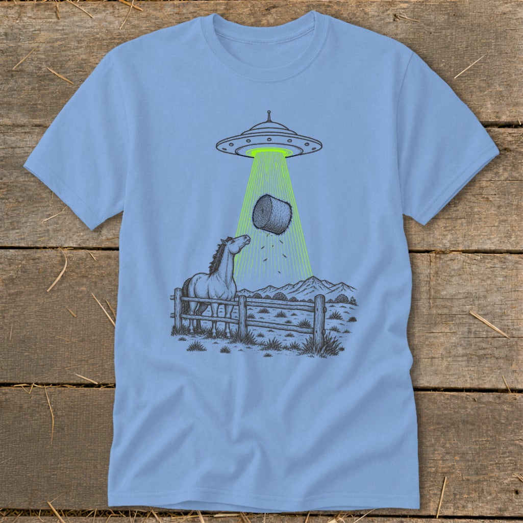 Horse looks up as UFO beam lifts hay bale from fenced field with mountains.