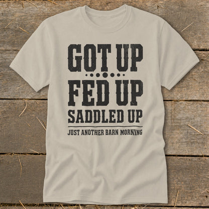 Tan t-shirt with black text: "GOT UP FED UP SADDLED UP JUST ANOTHER BARN MORNING".
