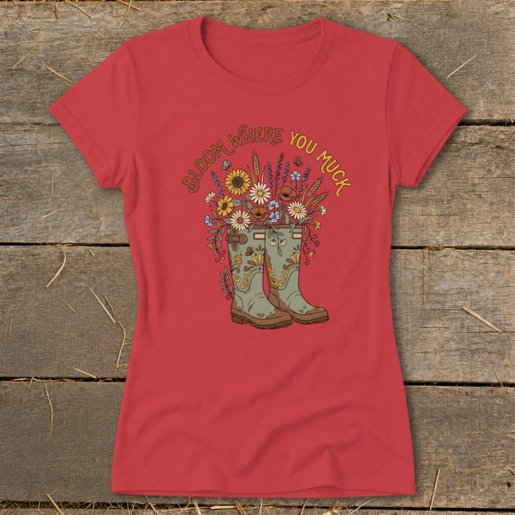 Red t-shirt with graphic of boots overflowing with flowers, and text "Bloom Where You Muck".