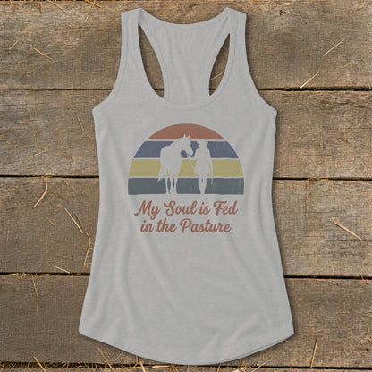 Gray tank top with horse and rider silhouette on striped sunset and text "My Soul is Fed in the Pasture."
