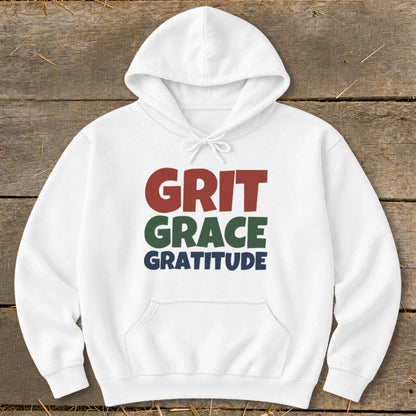 A white hooded sweatshirt with a front pocket, printed with "GRIT GRACE GRATITUDE" in red, green, and blue text.