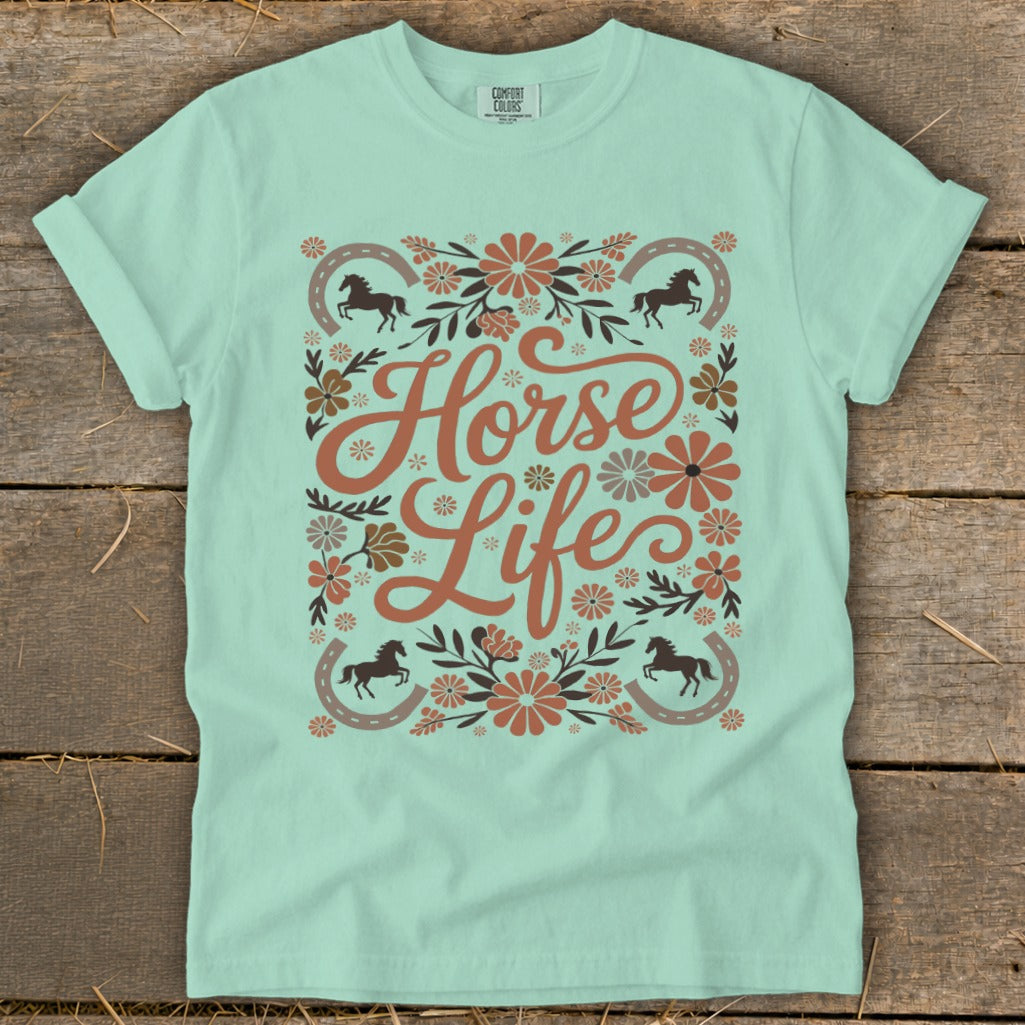 Light teal t-shirt with floral design, horses, horseshoes, and text "Horse Life".