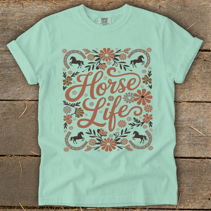 Light teal t-shirt with floral design, horses, horseshoes, and text "Horse Life".