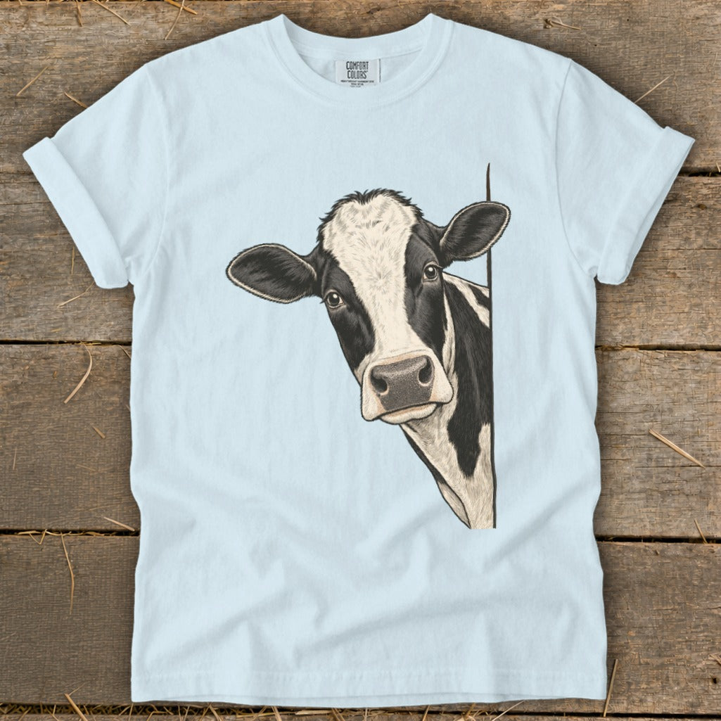 Light blue t-shirt with a black and white cow peeking from the right.