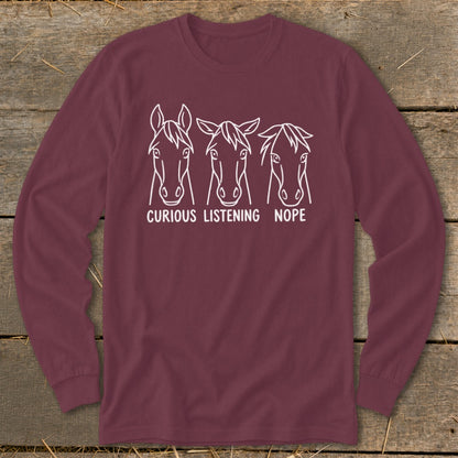 Maroon long-sleeve t-shirt featuring a white graphic of three horse heads with the captions Curious, Listening, and Nope.