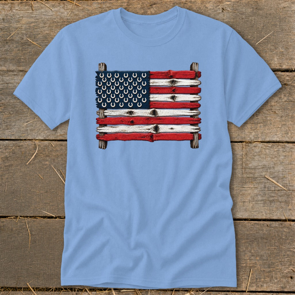 A light blue crewneck t-shirt featuring a rustic American flag design made of weathered wood planks and horseshoes.