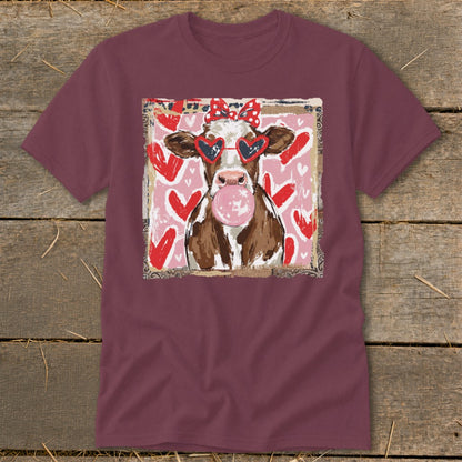 Cow wearing heart-shaped sunglasses and a red bow, blowing bubblegum.